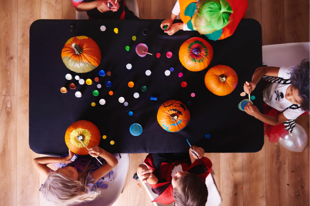 A birds eye view of children painting pumpkins.