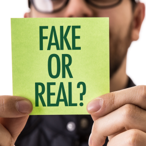 Image showing a man holding a post-it note, saying "Fake or Real?".